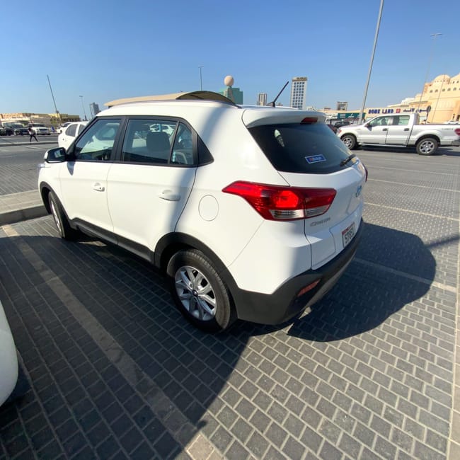 Biały suv na parkingu w ras al khaimah w uae, w tle meczet i inne auta.