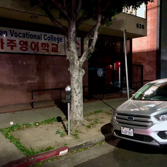 Nocny widok przy american vocational college w los angeles, z zaparkowanym srebrnym suv-em na ulicy.