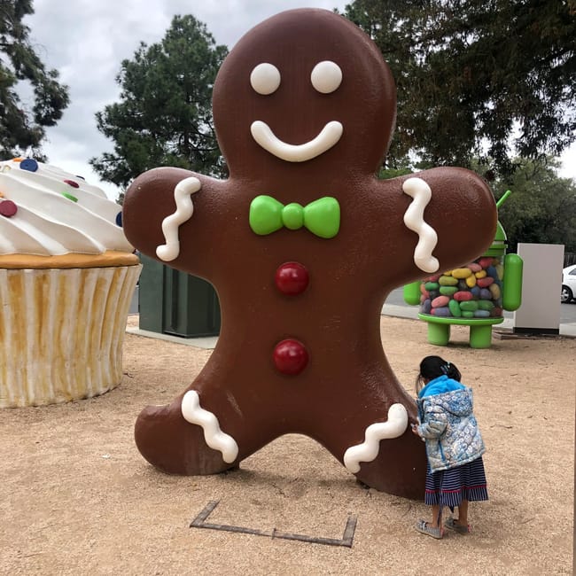 Gingerbread man w googleplex w mountain view, obok dziecka i dużych figur słodyczy.