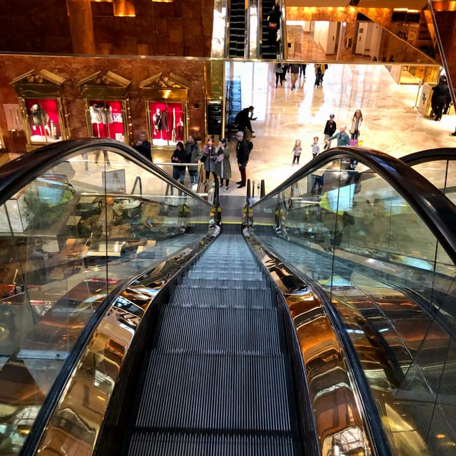 Wnętrze trump tower w nowym jorku z ruchomymi schodami i sklepami.