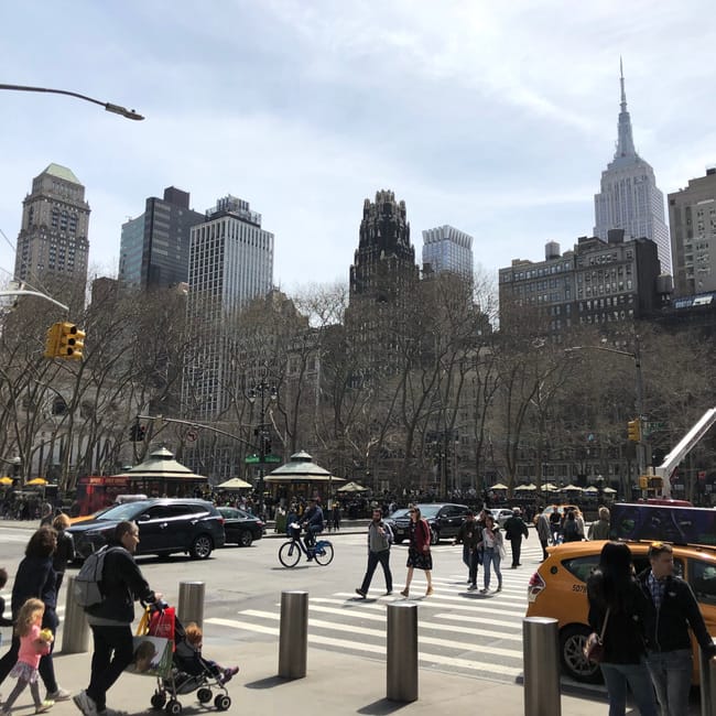 Bryant park w nowym jorku z drapaczami chmur i ruchem ulicznym w tle.