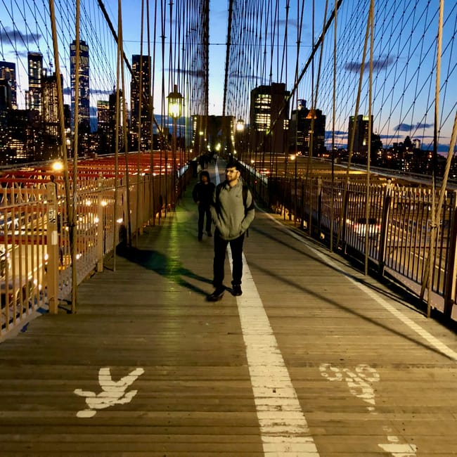 Most brooklyn bridge w nowym jorku o zmierzchu, z pieszymi i panoramą drapaczy chmur w tle