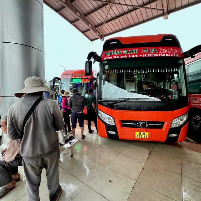 Dworzec autobusowy da lat w wietnamie z czerwonymi autobusami i pasażerami pod zadaszeniem.