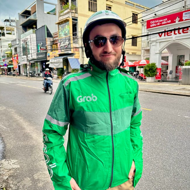 Kurier grab w da nang stoi na ulicy w zielonej kurtce i kasku.