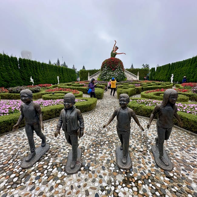 Ogród ba na hills w da nang z rzeźbami dzieci i kwiatową figurą tancerki.