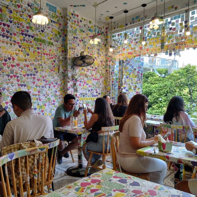 The note cafe w hanoi, kolorowa sala pełna karteczek z sercami i siedzących gości