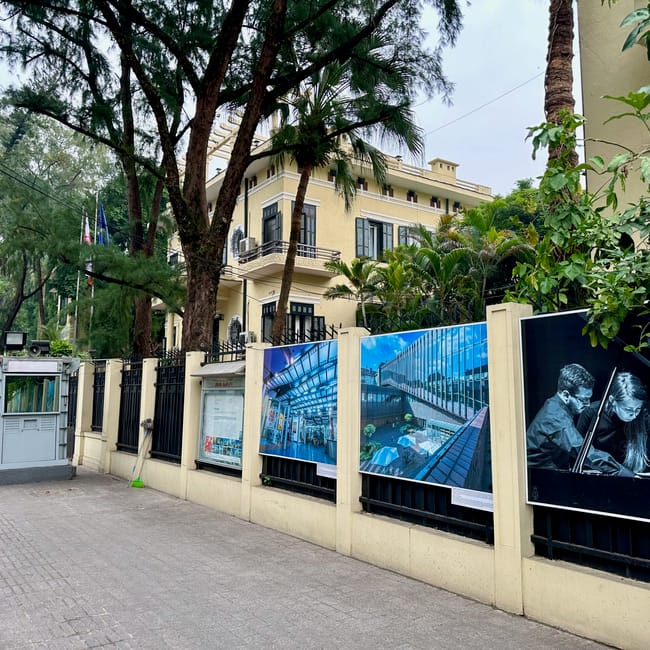 Ambasada polski w hanoi otoczona zielenią, z posterunkiem straży przy wejściu.