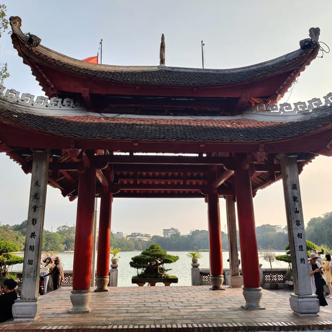 Świątynna brama ngoc son nad jeziorem w hanoi, z ludźmi na tarasie.