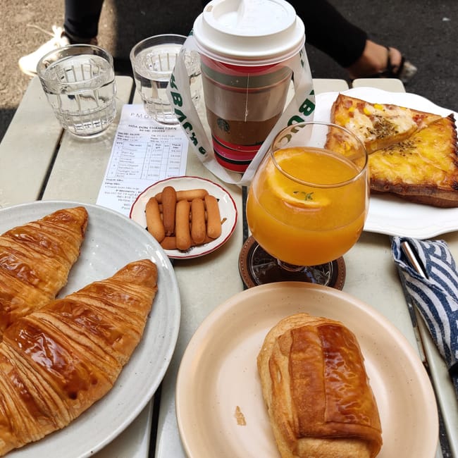 Śniadanie w hanoi: croissanty, napoje i tosty na stoliku w kawiarni.