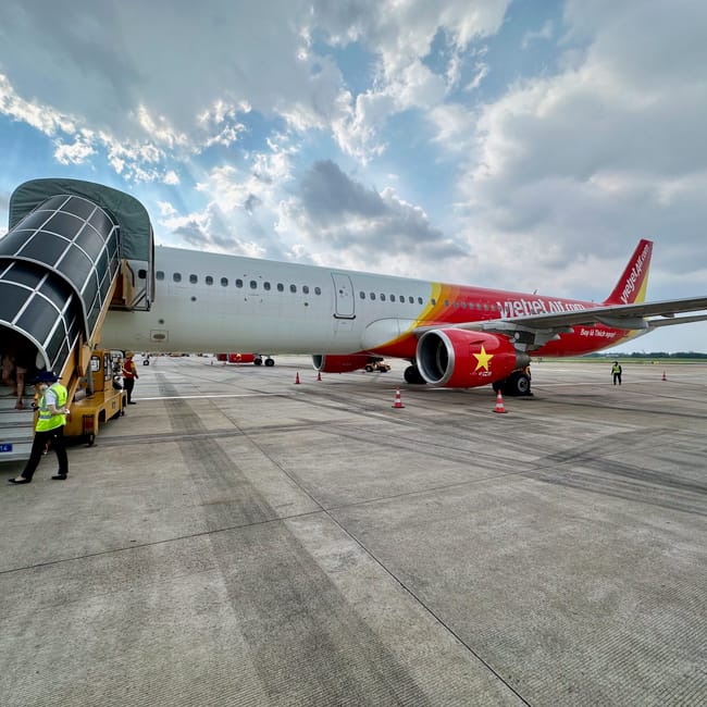 Samolot vietjet air na płycie lotniska w ho chi minh, z pasażerskim trapem i obsługą naziemną.