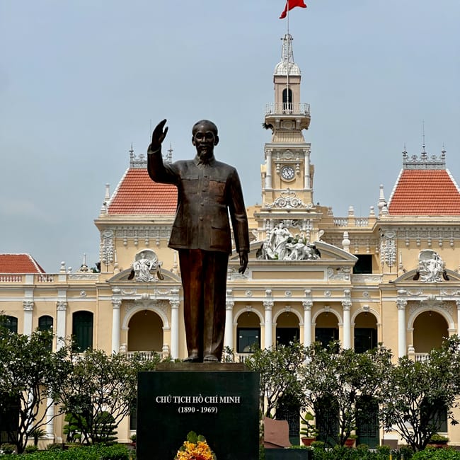Pomnik ho chi minha przed zabytkowym budynkiem z wieżą i czerwoną flagą w ho chi minh staue
