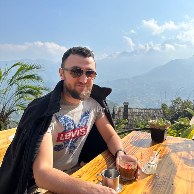 Mężczyzna przy stoliku w sa pa coffee & homestay w wietnamie, z widokiem na góry.