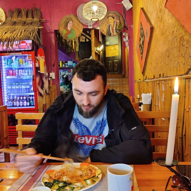 Mężczyzna je posiłek w restauracji w sa pa, przy stoliku z herbatą i świecą.