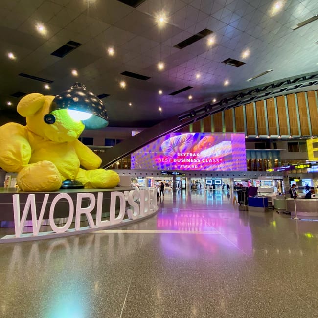Wnętrze lotniska doha w katarze z dużym żółtym misiem i napisem worldside.