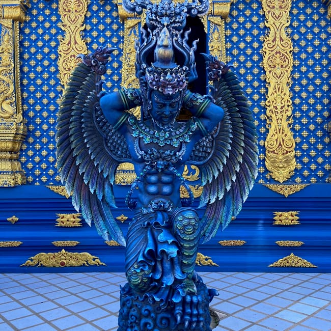 Rzeźba w wat rong suea ten w chiang rai, thailandia, na tle niebiesko-złotej ściany świątyni