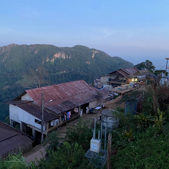Punkt widokowy pha hi village w chiang rai, z domami na zboczu i górą w tle.