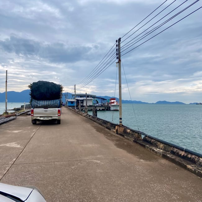 Molo na koh chang w tajlandii z samochodem i łodziami na tle morza