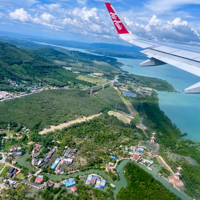Widok z samolotu airasia na zielone wybrzeże phuket w tajlandii, z kanałami i zabudową.