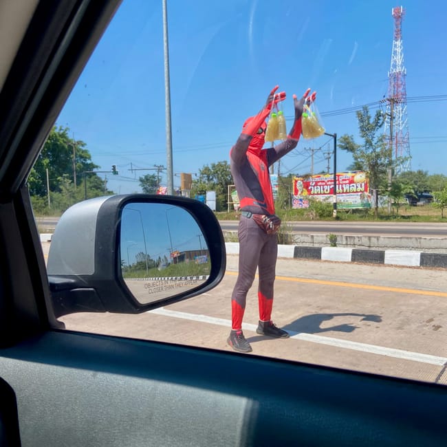 Delivery worker in a red uniform tossing bottles on a roadside in ubon ratchathani, thailand