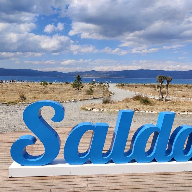 Napis „salda” nad jeziorem salda w turcji, z promenadą i górami w tle