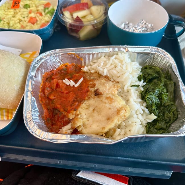 Posiłek na tacy w chengdu z ryżem, sosem pomidorowym, warzywami i bułką.