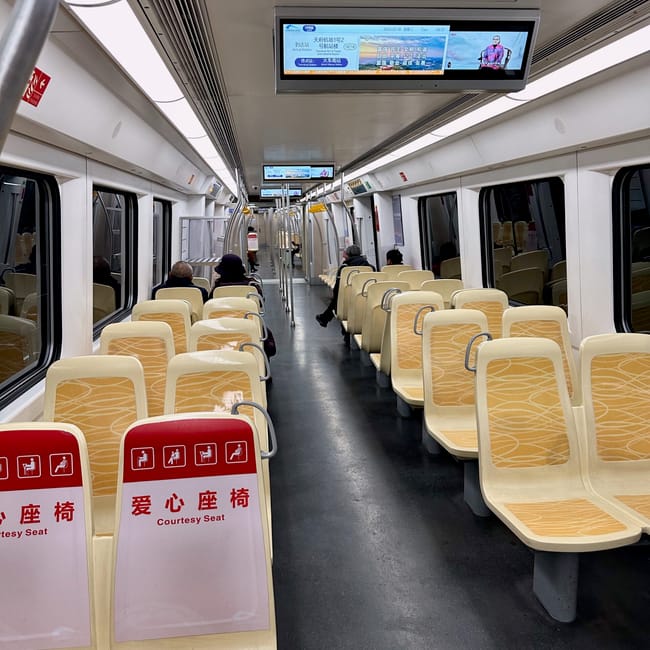 Wnętrze pociągu metra w chengdu z kilkoma pasażerami i oznaczonymi miejscami uprzejmości.