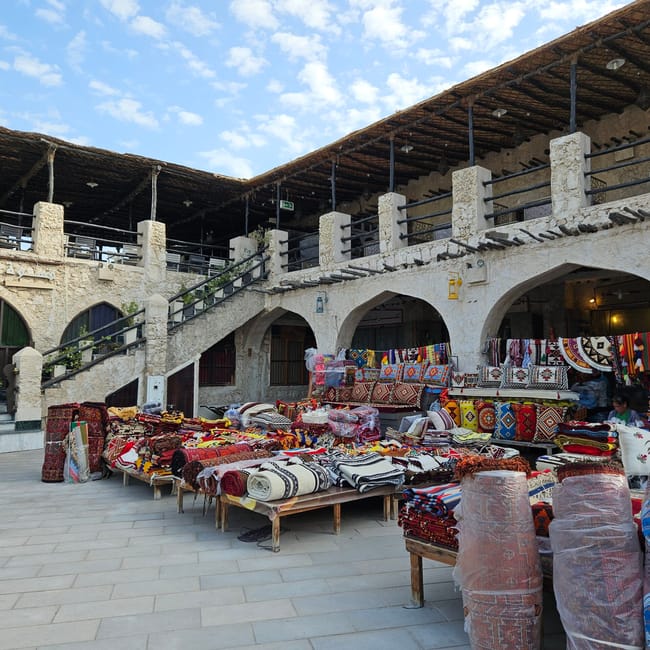 Souq waqif w doha z kolorowymi tekstyliami na straganach under arched arcade.