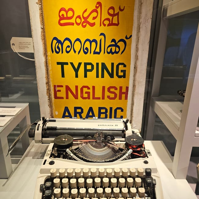 Maszyna do pisania przed żółtym szyldem z napisem „typing english arabic” w bin jelmood house w doha.