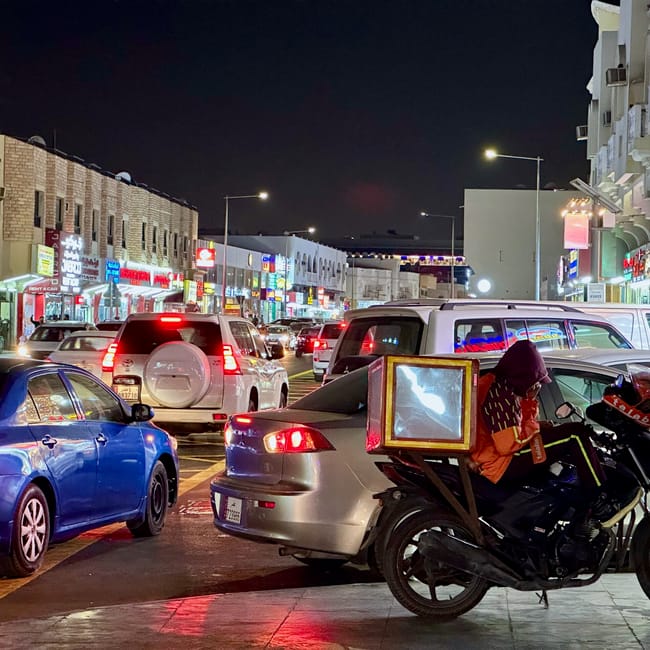 Nocny ruch uliczny w doha z korkiem, samochodami i motocyklem dostawczym.