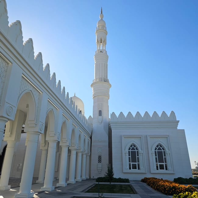 Meczet al sayedah khadeeja w abu zabi z białym minaretem i arkadami pod błękitnym niebem