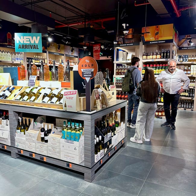 Sklep z alkoholami african eastern w dubaju z półkami pełnymi butelek i klientami.