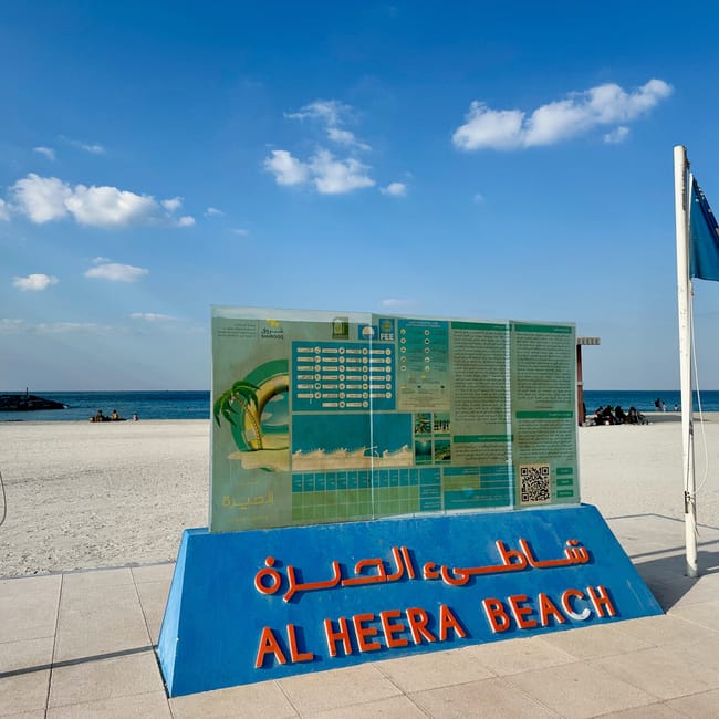 Wejście na al heera beach w sharjah z tablicą informacyjną i widokiem na morze
