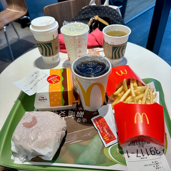 Posiłek mcdonald’s w shanghai foods: frytki, burger i kilka napojów na stole