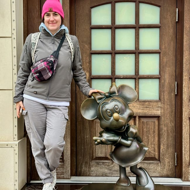 Kobieta stojąca obok brązowej figurki minnie mouse w szanghaju.