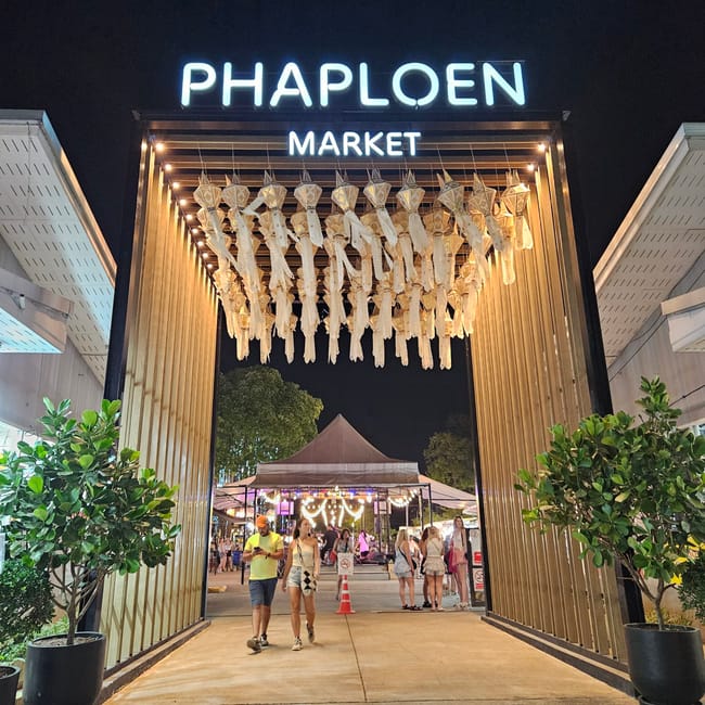 Wejście do phaploen market na chiang mai night bazaar w nocy, z podświetlonym łukiem i dekoracjami.