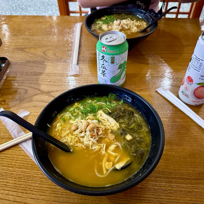 Zupa noodle z kurczakiem na stole w phuket, obok napoje i pałeczki