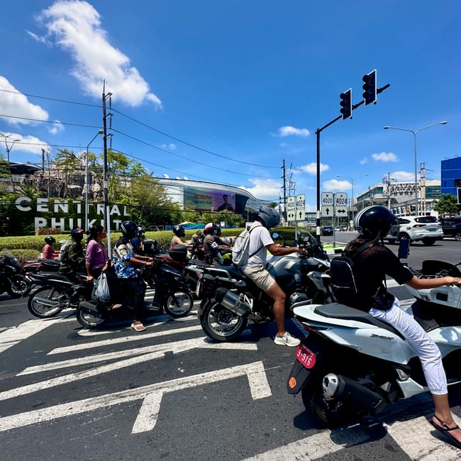 Motocykle i skutery stoją na skrzyżowaniu przy centrał phuket.