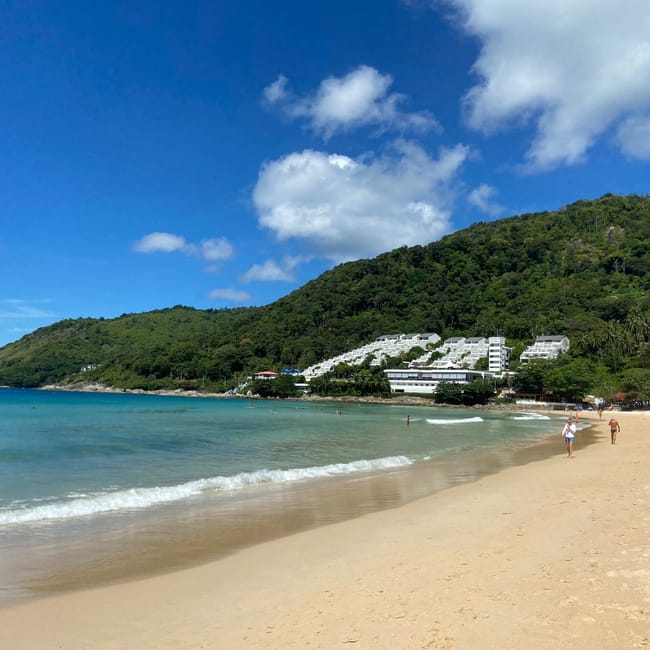 Plaża nai harn beach w phuket w tajlandii z turkusową wodą, wzgórzem i białymi hotelami.