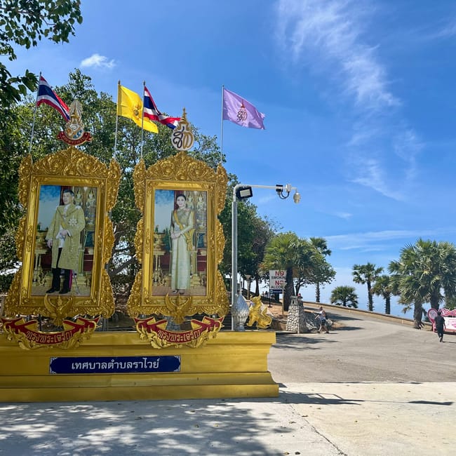 Promthep cape w phuket: ozdobny pomnik z portretami i flagami na tle nieba i palm