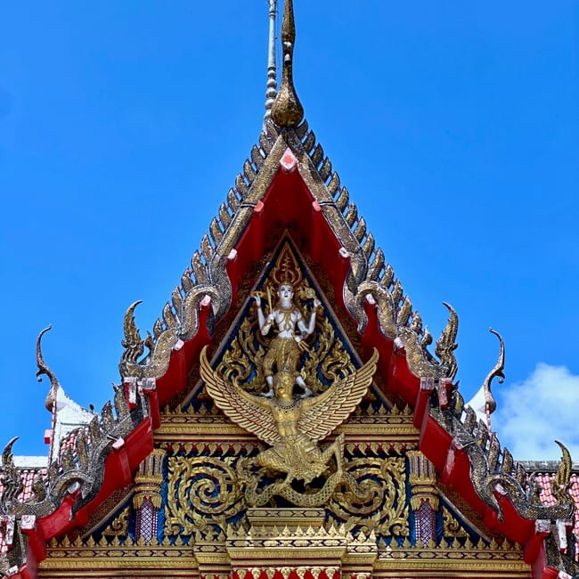 Szczyt bogato zdobionego dachu świątyni wat chalong w phuket, thailand, z niebieskim niebem w tle