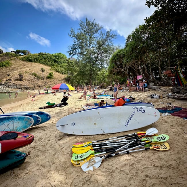 Plaża yanui beach w phuket z deskami sup, wiosłami i wypoczywającymi turystami.