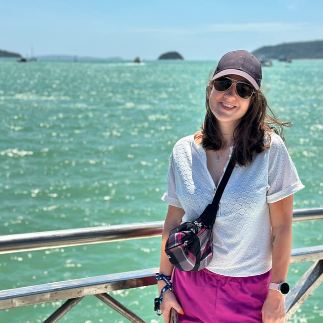 Kobieta na chalong pier w phuket, z morzem i łodziami w tle.