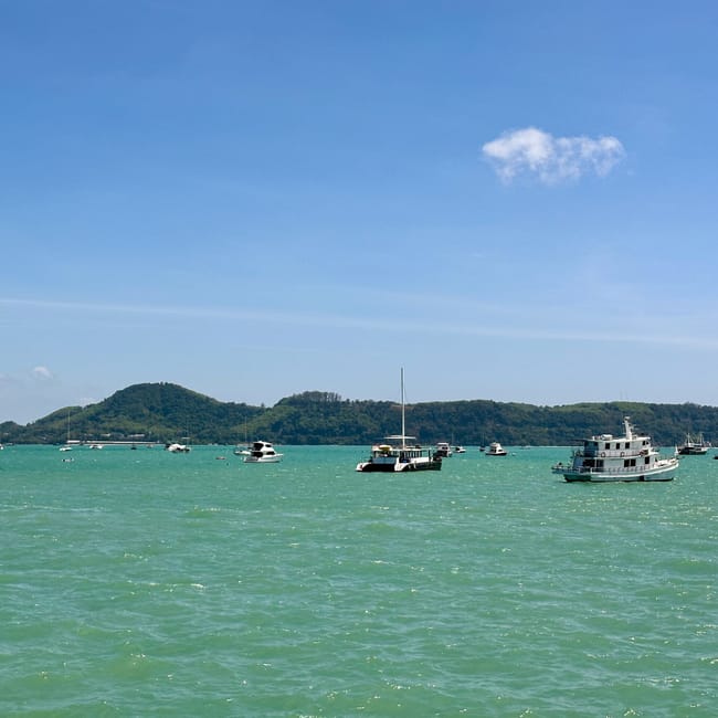 Phuket chalong pier w tajlandii, z łodziami na turkusowej wodzie i wzgórzami w tle
