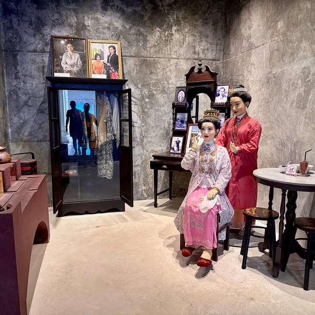 Ekspozycja w phuket thai hua museum z manekinami w tradycyjnych strojach i starymi fotografiami.