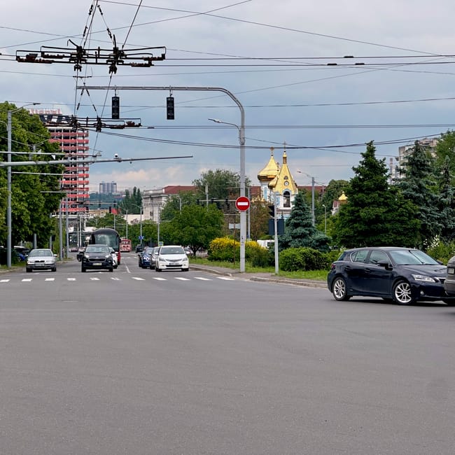 Cars driving on a multi-lane road in chisinau, moldova, under traffic lights and overhead wires near a gold church dome