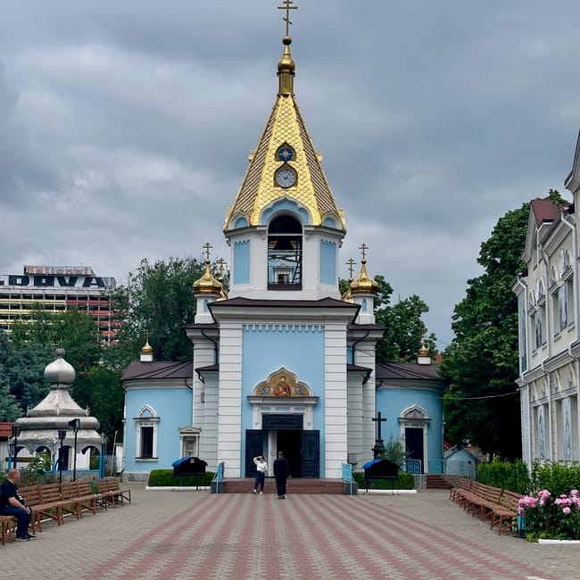 Moldova, chisinau city church with a golden spire and blue-and-white facade under a cloudy sky