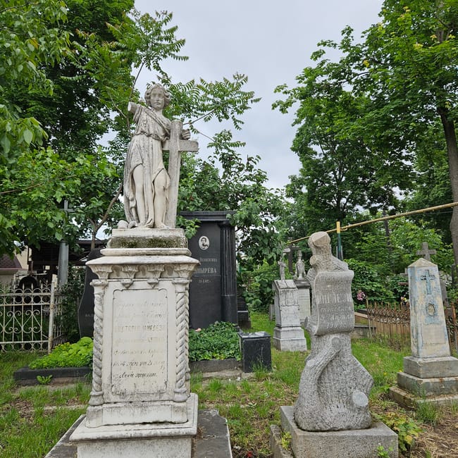 Nagrobki i rzeźba anioła na cmentarzu ormiańskim w chișinău, wśród zieleni.