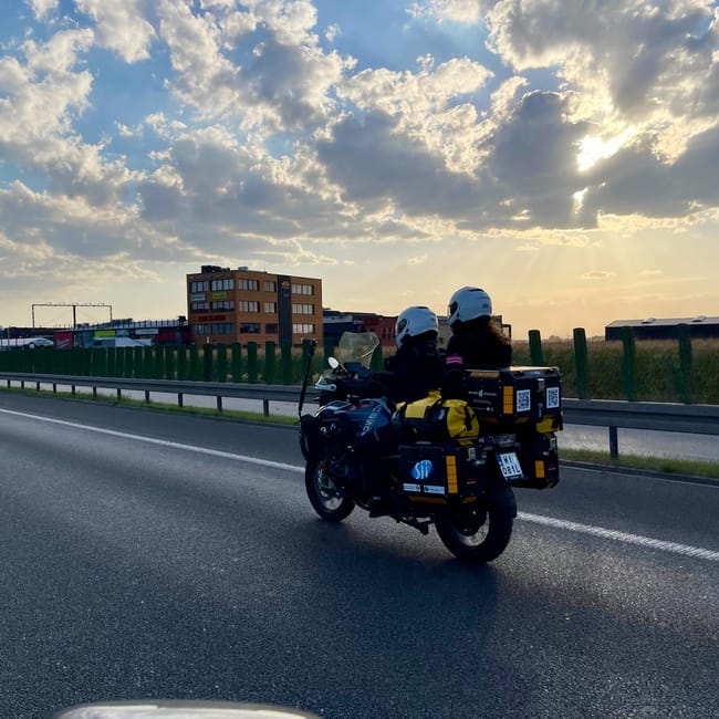 Dwoje motocyklistów jedzie ekspedycją po drodze pod dramatycznym niebem o zachodzie słońca