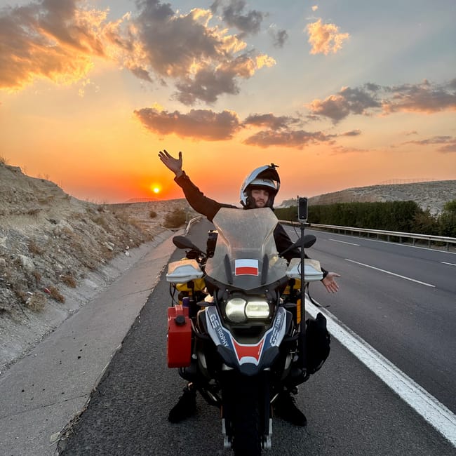 Motorcycle rider waving on the road at sunset during desert horizons motorcycle expedition in sanliurfa, turkey