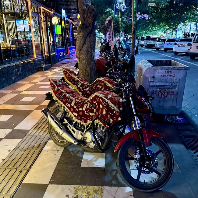 Desert horizons motorcycle expedition in sanliurfa, turkey: red motorcycle parked at a lit street café at night